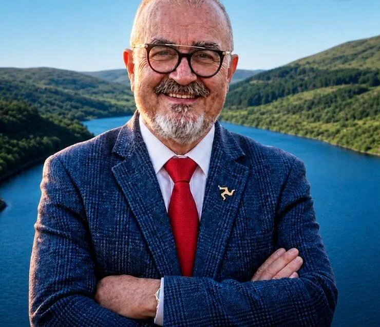 Andre Risha, arms crossed, in front of an Isle of Man valley and reservoir